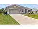 Well-maintained one-story home with a lush green lawn, gray exterior, and a two-car garage at 17200 Gulfspray Cir, Port Charlotte, FL 33948