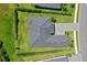 High angle of a house and backyard with a green lawn, neatly trimmed hedges, and gray roof at 17336 Sandpearl Rd, Venice, FL 34293