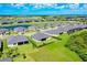 Aerial view of a residential area featuring modern houses with green lawns near a golf course and lake at 17336 Sandpearl Rd, Venice, FL 34293