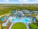 Drone shot of the community pool and tennis courts, with umbrellas, lush landscaping, and blue skies at 17336 Sandpearl Rd, Venice, FL 34293