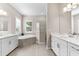 Bright bathroom featuring double sinks, a large tub, and a glass walk-in shower at 17336 Sandpearl Rd, Venice, FL 34293