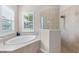 Bright bathroom featuring a luxurious soaker tub and tiled walk-in shower with glass surround at 17336 Sandpearl Rd, Venice, FL 34293