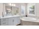 Bright bathroom featuring double sinks, a garden tub, and a tiled surround at 17336 Sandpearl Rd, Venice, FL 34293
