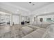 Open floor plan living room adjacent to kitchen, with white sectional sofa and access to a study and front entrance at 17336 Sandpearl Rd, Venice, FL 34293
