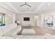 Bright living room with a tray ceiling, ceiling fan, large windows, and a comfortable white sectional sofa and ottoman at 17336 Sandpearl Rd, Venice, FL 34293