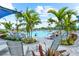 Resort-style pool area with palm trees, lounge chairs, and a blue awning for shade on a sunny day at 17336 Sandpearl Rd, Venice, FL 34293