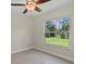 Bright bedroom featuring a ceiling fan, tile flooring, and a window with a wooded backyard view at 1983 Longstroth Ave, North Port, FL 34288