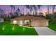 Charming single-story home with a well-manicured lawn, lush landscaping, and a two-car garage at dusk at 1983 Longstroth Ave, North Port, FL 34288