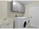 Well-equipped laundry room with washer, dryer, utility sink, and gray overhead cabinets at 1983 Longstroth Ave, North Port, FL 34288