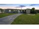 Inviting single-story home featuring a well-kept lawn and a long driveway under a vibrant twilight sky at 21524 Edgewater Dr, Port Charlotte, FL 33952
