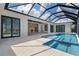 Screened-in pool area features tanning ledge, with view to the outdoor kitchen through the glass doors at 245 Lido Dr, Punta Gorda, FL 33950