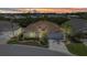 Beautiful home with a well-manicured lawn and landscaping, complemented by palm trees and a warm, inviting sunset at 24504 Buckingham Way, Punta Gorda, FL 33980