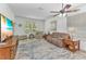Relaxing living room featuring a large window, ceiling fan, comfortable seating, and stylish wooden side tables at 24504 Buckingham Way, Punta Gorda, FL 33980