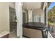 Relaxing covered spa area with privacy curtains, access to patio and view of lush greenery at 24504 Buckingham Way, Punta Gorda, FL 33980