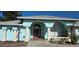 Light blue home featuring a charming arched entry, double red doors, and lush landscaping at 39 Norman St, Port Charlotte, FL 33954