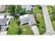Aerial shot of a cozy home with a well-manicured lawn, mature trees, and a paved driveway at 475 Whippoorwill Dr, Venice, FL 34293