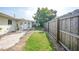 Well-maintained backyard with grassy area, a paved walkway, and a wooden fence at 475 Whippoorwill Dr, Venice, FL 34293