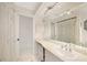 Bathroom features a long vanity with sink, large mirror, and an adjacent linen closet at 475 Whippoorwill Dr, Venice, FL 34293