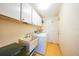 A functional laundry room with overhead cabinets, a utility sink, and a washer and dryer at 475 Whippoorwill Dr, Venice, FL 34293