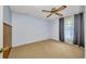 A comfortable bedroom with neutral carpet, a ceiling fan, and curtains that provide a view of the backyard at 769 Crestview Nw Cir, Port Charlotte, FL 33948