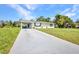 Single-story home features a long driveway, carport, well-maintained lawn, and green landscaping at 769 Crestview Nw Cir, Port Charlotte, FL 33948