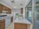 Classic kitchen featuring wood cabinets, white appliances, and view to the lanai through a pass-through window at 769 Crestview Nw Cir, Port Charlotte, FL 33948