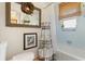 A bathroom with decorative accents such as a floral wreath, framed art, towel rack, and woven shade in the window at 825 Via Tunis, Punta Gorda, FL 33950