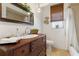 A traditional bathroom featuring a wood vanity, decorative mirror, a privacy shade, and a peek at the shower at 825 Via Tunis, Punta Gorda, FL 33950