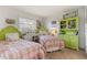 Sunlit bedroom with twin beds, green wicker headboards, decorative art, and a painted cabinet at 825 Via Tunis, Punta Gorda, FL 33950