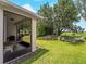 Backyard with lush green grass, a mature shade tree and an inviting screened in lanai with a grill at 8814 Tuscany Isles Dr, Punta Gorda, FL 33950
