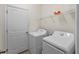 A laundry room features a washer, a dryer, tiled flooring, a storage shelf, and a utility closet door at 8814 Tuscany Isles Dr, Punta Gorda, FL 33950