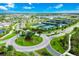 An aerial view shows a community with a round-about entry, tennis courts, lakes, and homes under a blue sky with white clouds at 14846 Contenta Loop, Bradenton, FL 34211