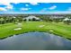 Scenic aerial view of a golf course with a pond and clubhouse, set against a backdrop of a partly cloudy sky at 14846 Contenta Loop, Bradenton, FL 34211