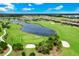 Picturesque aerial view of a golf course with a pond, sand traps, and surrounding homes under a bright blue sky at 14846 Contenta Loop, Bradenton, FL 34211