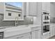 Modern kitchen with farmhouse sink, double oven, marble countertops, gray subway tile backsplash, and light gray cabinets at 14846 Contenta Loop, Bradenton, FL 34211