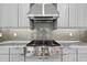 Modern kitchen with stainless steel gas range and hood, gray subway tile backsplash, and light gray cabinets at 14846 Contenta Loop, Bradenton, FL 34211