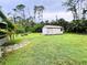 View of the backyard with a shed, surrounded by lush grass and trees at 15090 Rebecca Ave, Port Charlotte, FL 33953