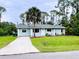 Charming single-story home with a well-maintained lawn, palm tree, and a long concrete driveway at 15090 Rebecca Ave, Port Charlotte, FL 33953