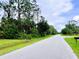 Picture of the street in front of the home with lots of tall trees at 15090 Rebecca Ave, Port Charlotte, FL 33953