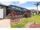 Well-manicured backyard featuring a screened-in pool, paver walkway, and tropical landscaping at 8178 Arlewood Cir, Port Charlotte, FL 33981