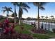 Waterfront backyard featuring a lush lawn, tropical landscaping, and canal view at 8178 Arlewood Cir, Port Charlotte, FL 33981