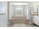 This bathroom features a large soaking tub, white pillars, plantation shutters, and neutral walls and floors at 8178 Arlewood Cir, Port Charlotte, FL 33981
