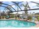 Beautiful pool and patio area with a screen enclosure, tropical plants, and tranquil water views at 8178 Arlewood Cir, Port Charlotte, FL 33981