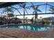 Stunning screened-in pool with brick surround, tropical plants, and river views offer a relaxing outdoor retreat at 8178 Arlewood Cir, Port Charlotte, FL 33981