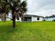 The backyard features a covered screened lanai and large yard, shaded by a palm tree at 8917 Sawyer Cir, North Port, FL 34288