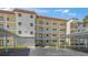 Low angle view of a multi-story condo with white facade, red tiled roof, balconies, and covered parking at 915 Beach Rd # 215, Siesta Key, FL 34242