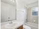 A clean bathroom features a sink with storage, a toilet, and a shower-tub combination with white tile surround at 5260 Jessamine Ave, North Port, FL 34291