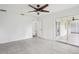 A spacious bedroom is shown with a ceiling fan, sliding glass doors to the outside, and a door to the hallway at 5260 Jessamine Ave, North Port, FL 34291