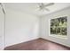 Bright bedroom featuring dark laminate floors, a ceiling fan, and a window showcasing the lush landscape at 5260 Jessamine Ave, North Port, FL 34291