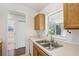 Kitchen space featuring a double sink, wood cabinets, and view into the screened outdoor patio at 5260 Jessamine Ave, North Port, FL 34291